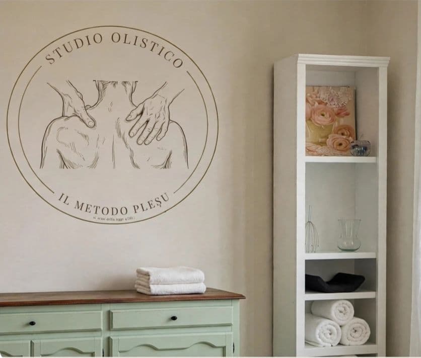 Il sigillo dello studio dipinto sulla parete, sopra una credenza verde salvia con asciugamani piegati